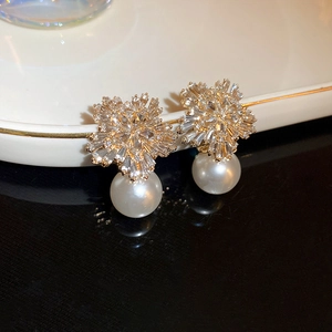Detailed macro of crystal flower and white pearl earring on elegant ceramic base