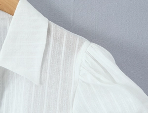 Macro shot of white shirt collar and pleated puff sleeves with vertical stripe texture