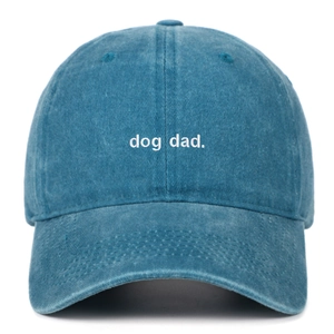 Detailed view of dog dad white embroidery on blue washed cotton baseball cap