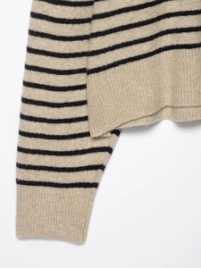 Détail d'un pull rayé montrant le tissu beige en laine mélangée et les poignets côtelés