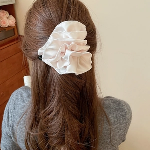Détail d'une grande pince à cheveux fleurie en tissu rose clair à volants