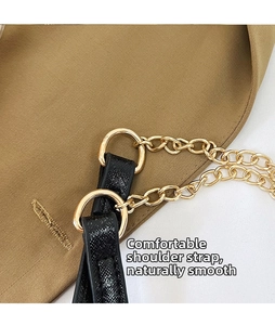 Detail of black textured leather strap with polished gold metal chain and rings