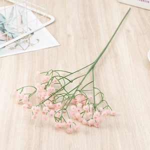 Close-up of realistic pink artificial baby's breath flowers on a light wood tabletop