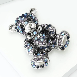 Detailed macro view of a silver bear brooch with blue and purple crystal inlay