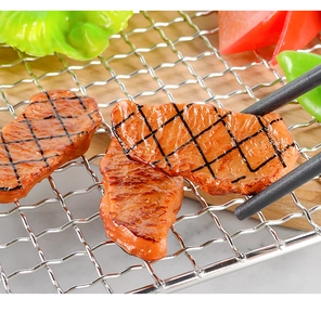 Macro shot of realistic fake roasted beef model with grill marks and lettuce on a rack