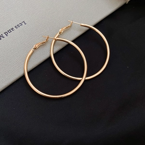 Macro shot of large polished golden hoop earrings on a textured minimalist background