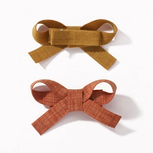 Close-up of yellow and caramel linen fabric hair bow clips with detailed textile texture