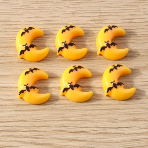 Detailed view of yellow resin moon cabochons with bat prints for DIY crafts