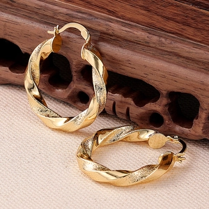 Detail von goldenen Creolen mit spiralförmiger Textur und polierter Metalloberfläche