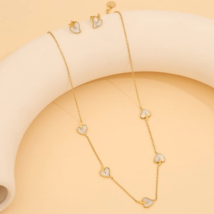 Détail du collier et des boucles d'oreilles dorés avec pendentifs en nacre blanche