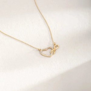 Detail of gold heart and infinity symbol necklace pendant with sparkling small diamonds