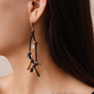 Detail of drop tassel earrings with gold and silver leaf pendants on black cord