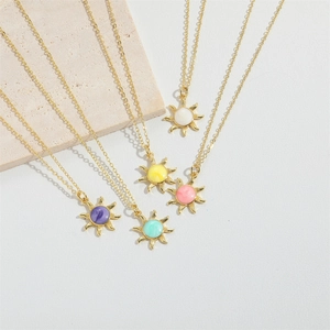 Golden sun pendant necklaces with colorful enamel centers on elegant stone display