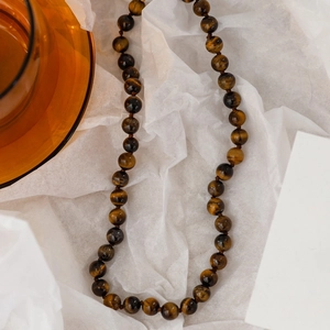 Maillard tiger eye beaded necklace for women on white textured background