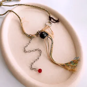 Collier en corde tissée style ethnique avec glands colorés et perles noires et rouges
