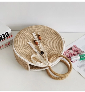 Detail of round straw bag with beige weaving, white lace ribbons, and wooden beads