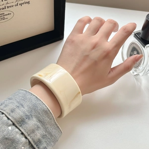 Detail eines minimalistischen Acetat-Armreifs mit Marmormuster an einem Model