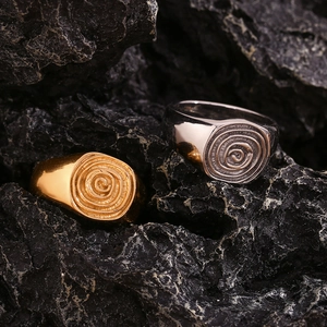 Macro detail of gold and silver signet rings with spiral pattern on black rock