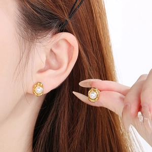 Gros plan sur les boucles d'oreilles perles dorées avec base irrégulière et perle blanche