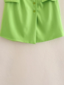 Detailed view of lime green woven skirt with button closures and pocket flap accents