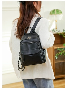 Close-up of black PU leather backpack with rivet detail and multiple zip compartments