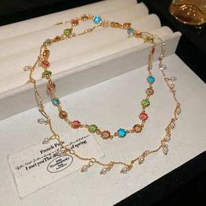 Detail einer mehrlagigen goldfarbenen Halskette mit bunten Edelsteinen und Perlen in Box