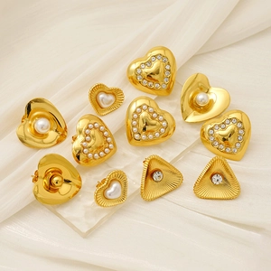 Detail of assorted gold heart and pearl stud earrings on white silk and acrylic
