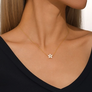 Detail of s925 gold flower pendant with clear zircon crystals on woman's neckline