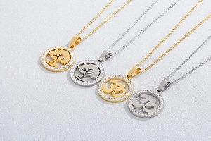 Detail of crystal halo pendants featuring Tree of Life and Om symbols in gold and silver