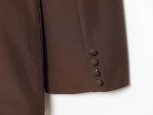 Détail de manche de veste marron foncé avec quatre boutons recouverts et texture fine