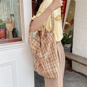 Detail of yellow checkered canvas tote bag with vegetable print on a casual shoulder strap