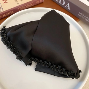 Detail of elegant black satin bow hair claw with handcrafted beads and lace trim finish