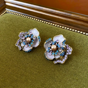 Detail of vintage flower stud earrings with enamel petals and central pearl inlay