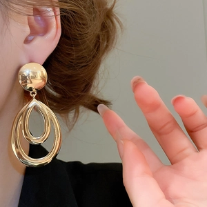 Gros plan détaillé de boucles d'oreilles pendantes doubles gouttes dorées sur un modèle