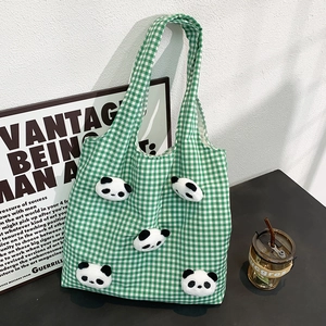 Close-up of green checkered canvas tote bag with five cute 3D plush panda heads decoration
