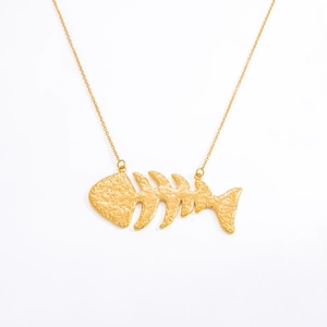 Detailed macro view of 18k gold fishbone pendant with hammered texture and metallic luster