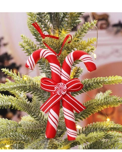 Close-up of red and white striped candy cane ornaments on a snowy Christmas tree branch