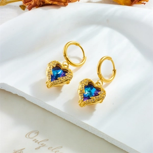 Elegant gold heart earrings with blue crystal and diamond accents on a white stone tray