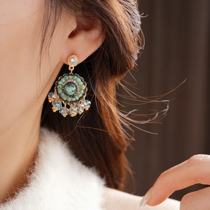 Dettaglio di orecchini vintage boho con pietra verde e perline colorate sulla modella