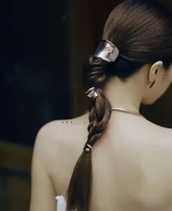 Close-up of three polished silver metal hair hooks styled on a woman's low braided ponytail