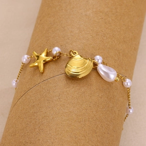 Close-up of golden sea star and shell charms with white pearls on a summer beach necklace