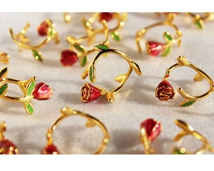 Detailed macro view of gold-tone French rose earrings with red and green enamel coating