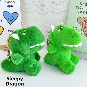 Close-up of green plush dinosaur keychains with metal rings on decorative background