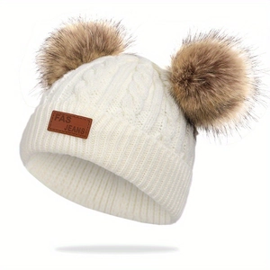 Texture détaillée du bonnet d'hiver blanc pour bébé avec deux pompons marrons et étiquette cuir