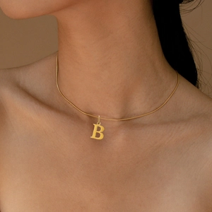 Close-up of gold snake chain necklace featuring a bold letter B pendant on model