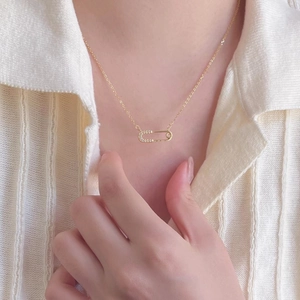 Macro detail of a 925 silver gold-plated safety pin necklace with pavé crystal accents