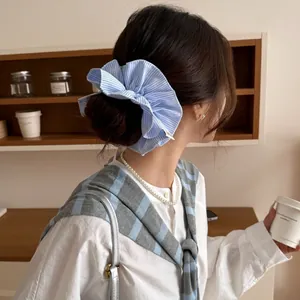 Blue and white striped scrunchie with layered ruffles shown in a soft home lifestyle setting