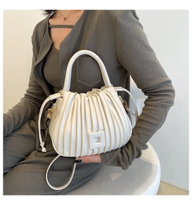 Detail of white pleated PU leather bucket bag with top handle and shoulder strap