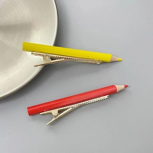 Détail de pinces à cheveux crayon mignonnes en jaune et rouge sur des clips en métal doré
