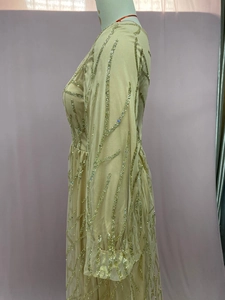 Detail von champagner-goldenen Pailletten auf langärmeligem Mesh-Abendkleid mit Textur